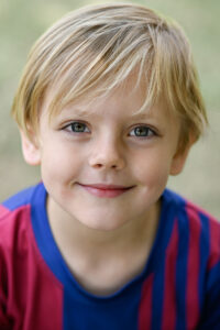 Porträt von einem lächelnden, blonden Jungen in einem gestreiften Trikot